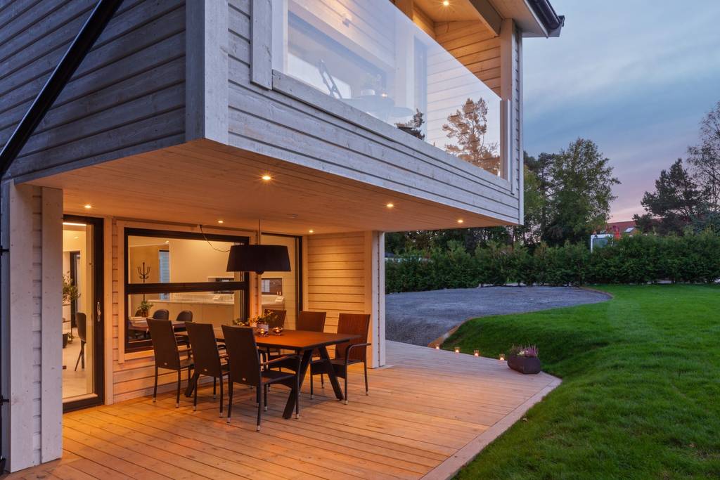 Altan med matplats under tak vid modern villa.